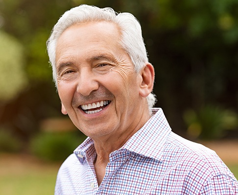 Senior man standing in field smiling